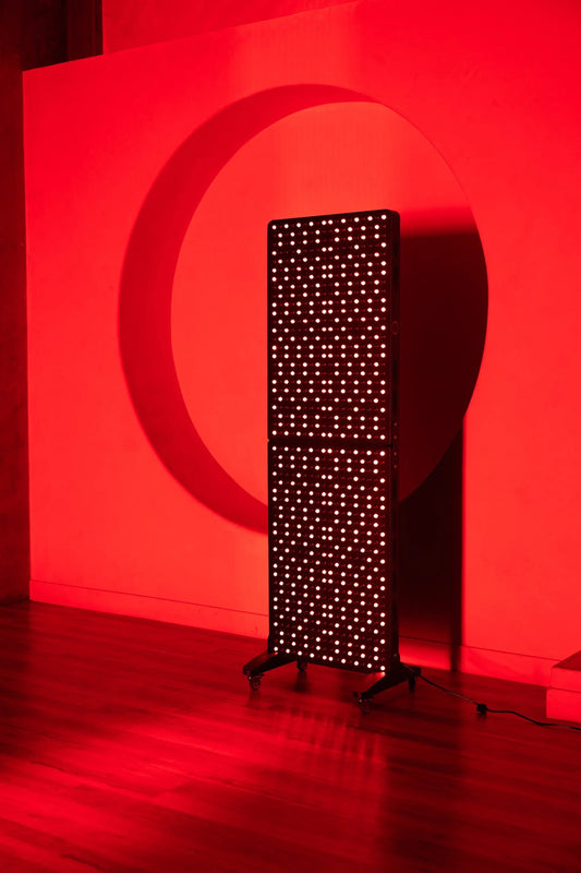 A light therapy panel standing against a red wall, showcasing its powerful LED design for wellness.