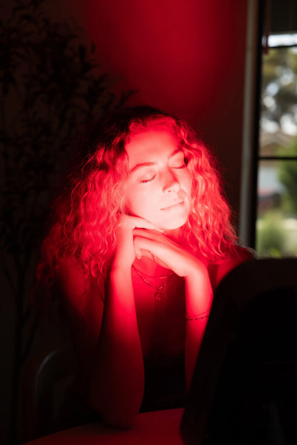 A woman experiencing the benefits of The Small Panel, a red light therapy device for pain relief and healing.