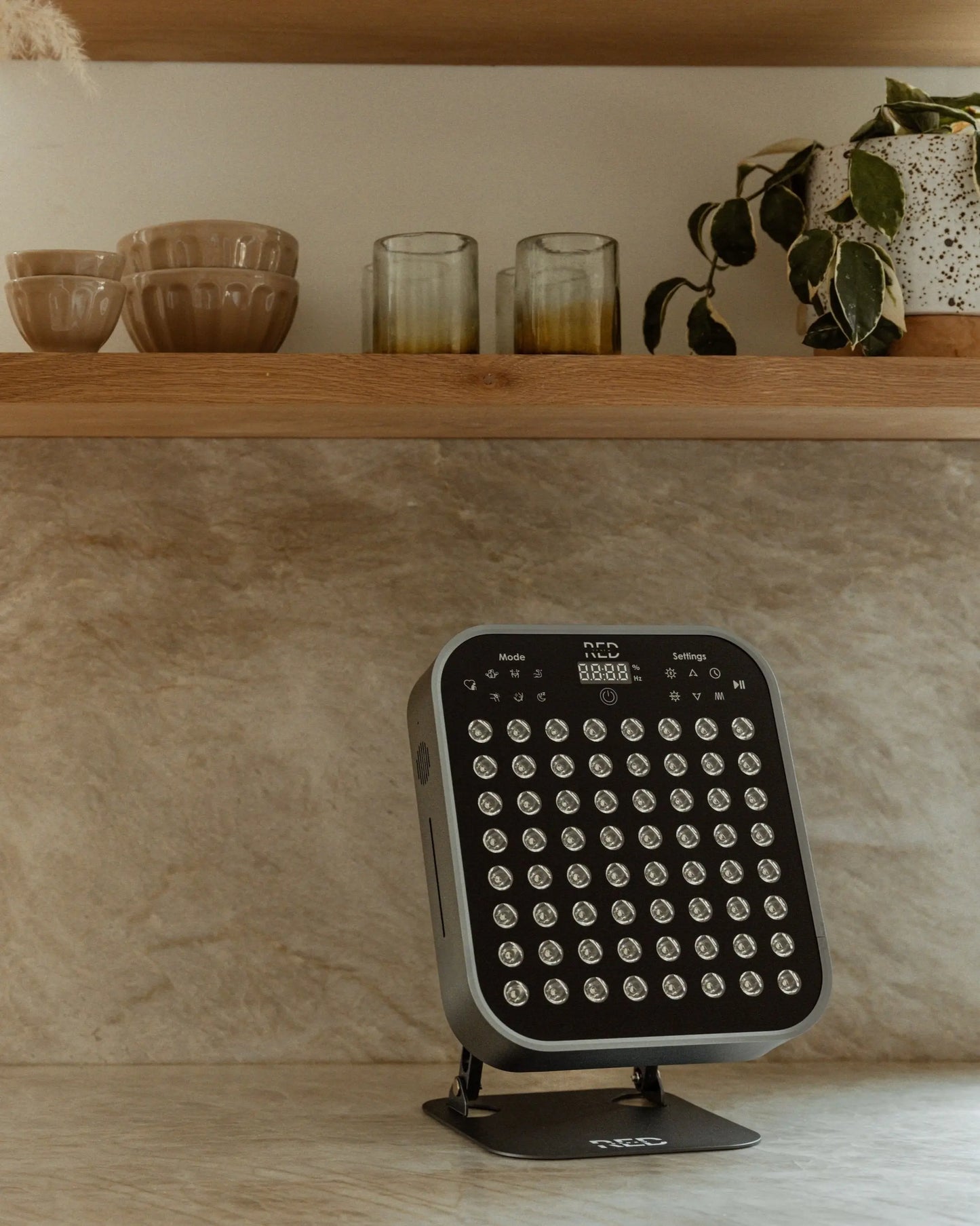 The Small Panel red light therapy device on a countertop, designed for pain relief and muscle recovery.